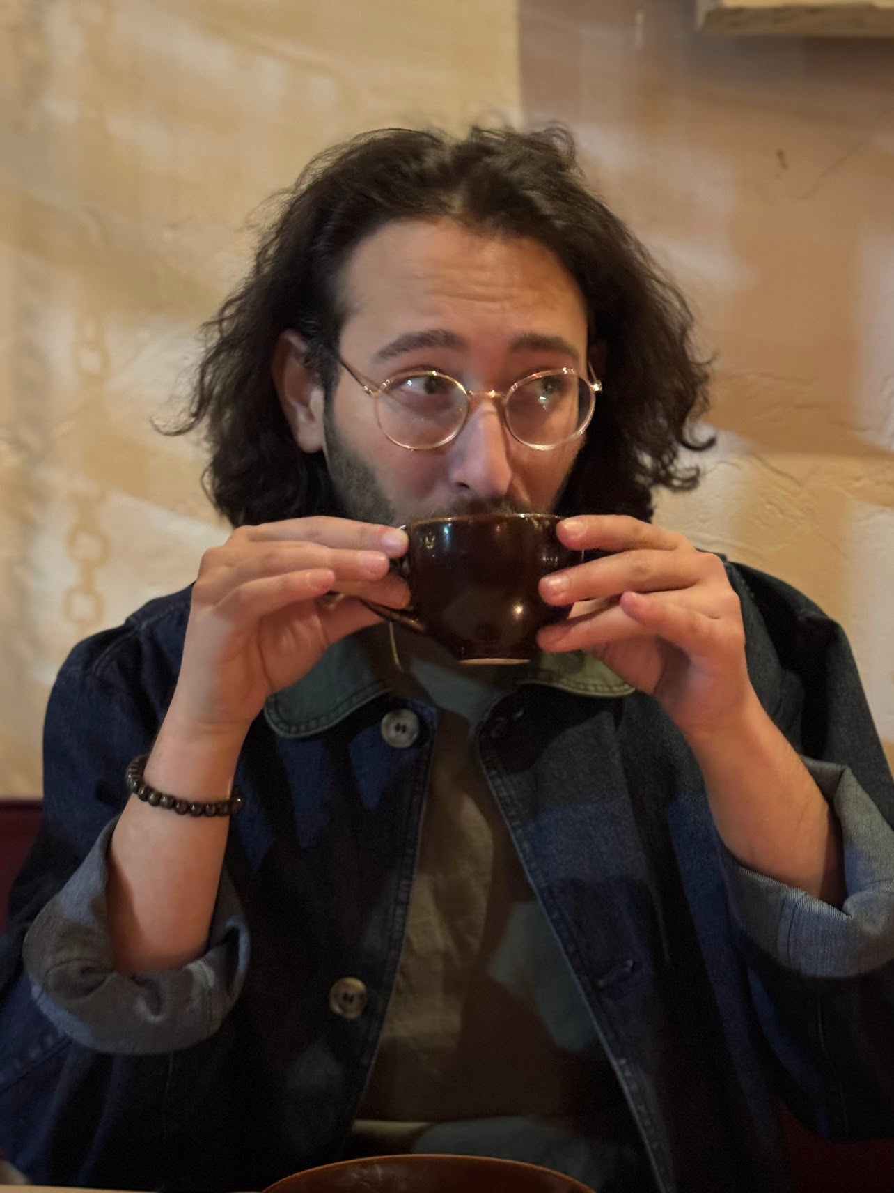 Avi Goldman sipping from a coffee cup, looking off to the side
